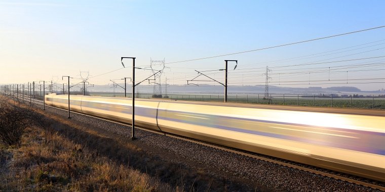 Motion blur photo of high speed train running at full speed reflecting off the sunset